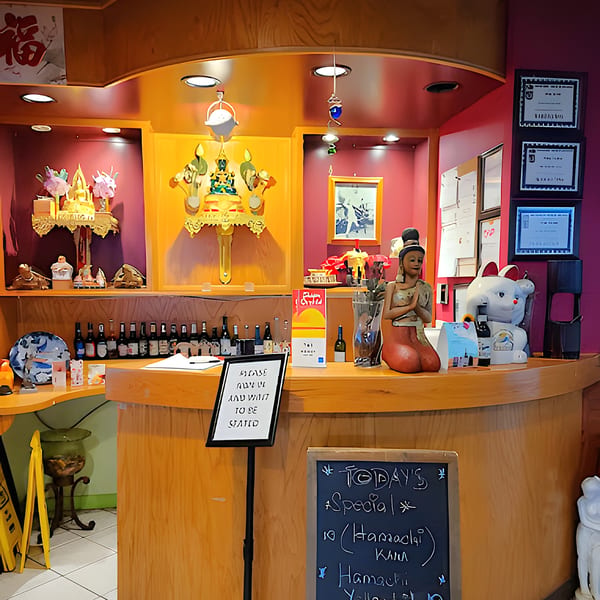 The host stand at Siam Orchid Cocoa Beach, adorned with Thai decor and a specials board.