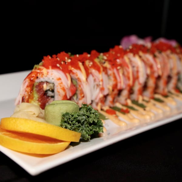 A long plate of Siam Orchid's vibrant sushi rolls, garnished with lemon, wasabi, and greens.