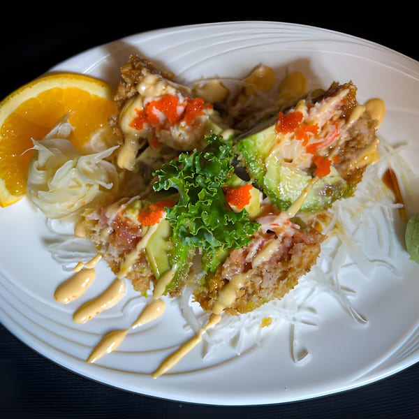 Crispy Thai dish with avocado, crab, roe, and sauce, garnished with orange and lettuce.