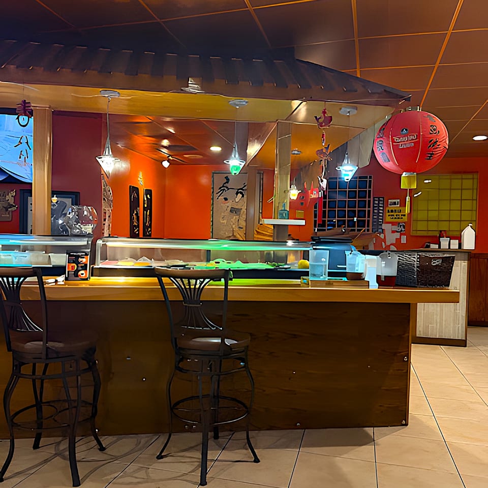 A sushi bar with two stools, red walls, and a large red lantern at Siam Orchid.