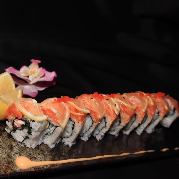 Siam Orchid's sushi roll with salmon, lemon slices, and red roe, garnished with a pink orchid.