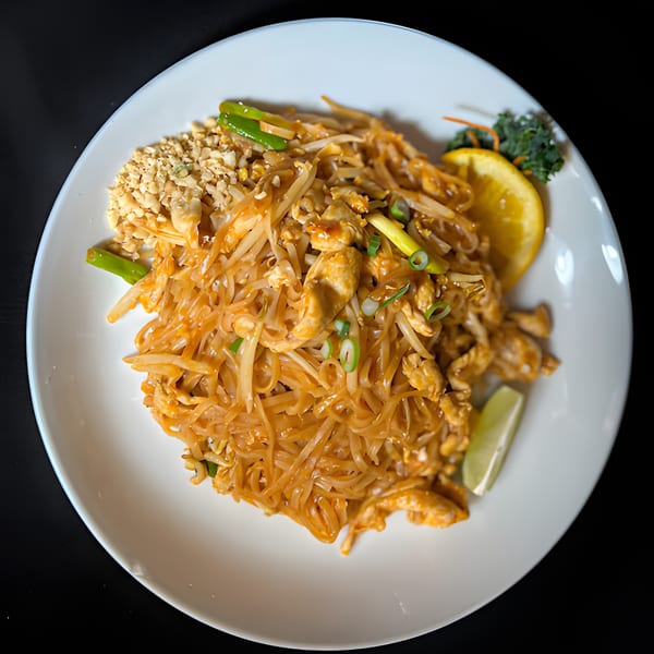 Siam Orchid Cocoa Beach's chicken Pad Thai with peanuts, lime, and orange on a white plate.